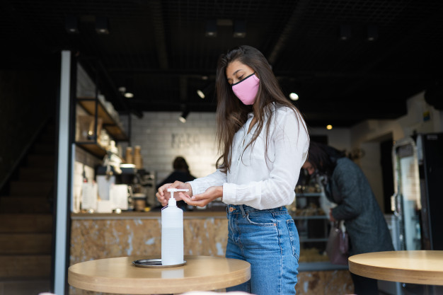 woman using sanitizer gel-cleans-hands-coronavirus virus cafe